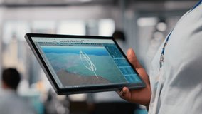 Close up of engineer working on futuristic vertical wind turbine CAD design used for green energy research. Worker using digital modeling tablet app to upgrade wind VAWT energy generator gear - Powered by Shutterstock - Get 15% off with code: PIKWIZARD15