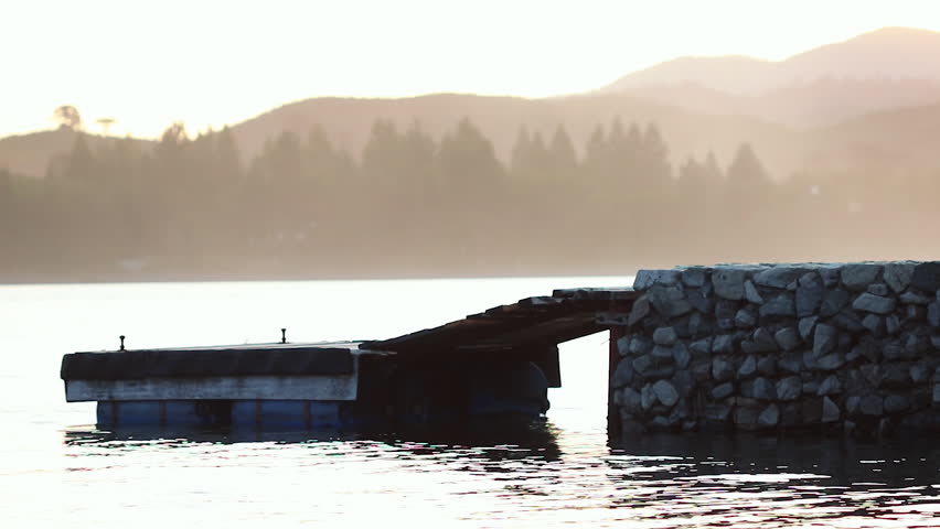 Backlit lakeside dock and stone pier at dusk
