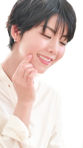 Vertical video of a beautiful Japanese woman ideal for beauty imagery. Confirming skincare by touching her cheek.