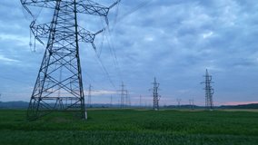 Dolly shot of electricity pylons across a vast agricultural landscape under twilight, blending rural tranquility with modern power transmission. - Powered by Shutterstock - Get 15% off with code: PIKWIZARD15