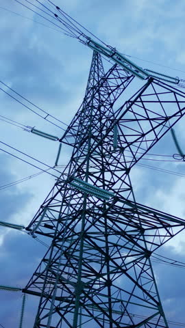 Powerful electricity pylons stretch across a vibrant sunset sky, symbolizing sustainable energy infrastructure. Towering steel structures with intricate lattice designs support high-voltage power.