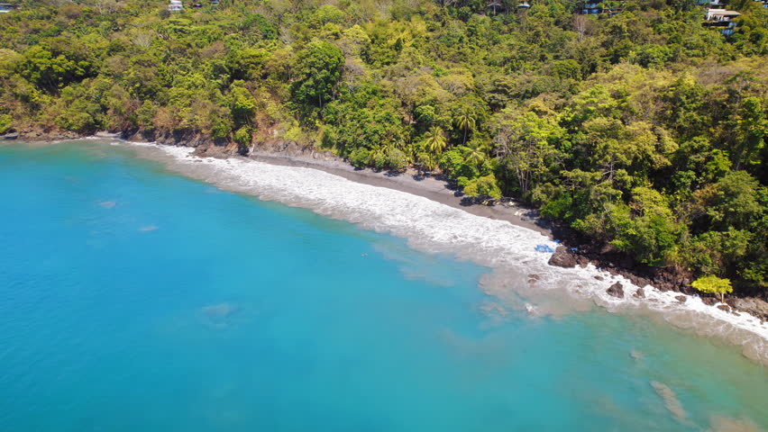 Shoreline with sandy beach in Costa Rica with turquoise water and jungle backdrop