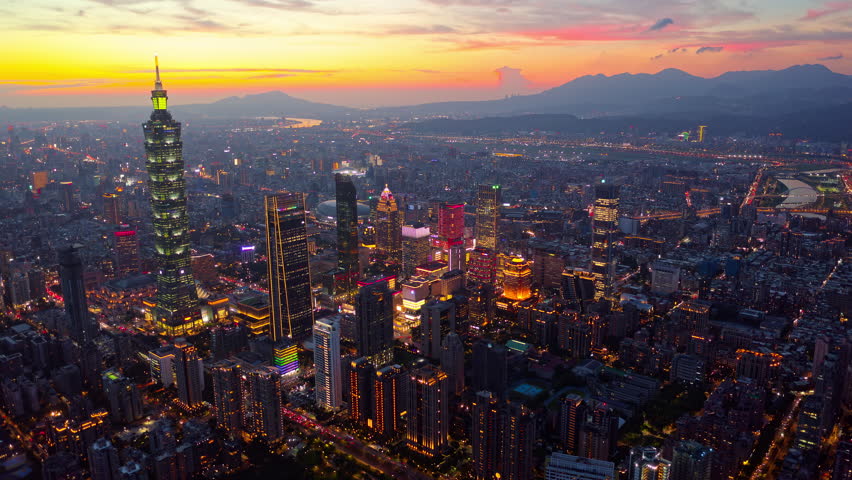 Aerial hyperlapse of Downtown Taipei at dusk, the vibrant capital city of Taiwan, with 101 Tower standing out amid skyscrapers in XinYi Commercial District and city lights dazzling under twilight sky
