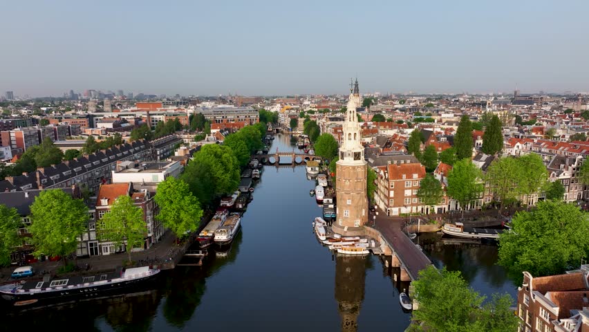 Drone footage of Montelbaanstoren, boats, and historic canal houses in Amsterdam.
