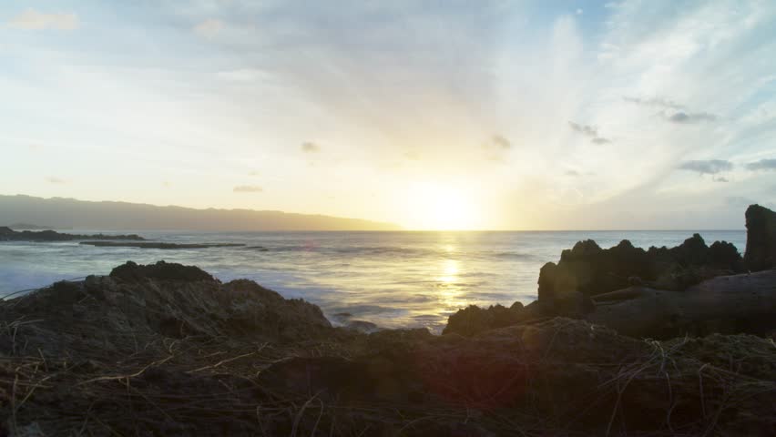 Timelapse of a sunset on the North Shore of Oahu in Hawaii with surfers in the ocean