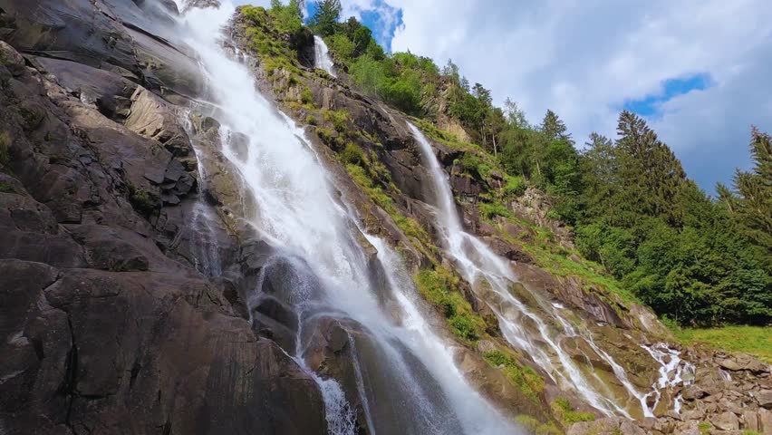 experience the beauty of a waterfall cascading down rocks. enjoy the scenic view of nature and travel to this amazing destination. nature at its best!