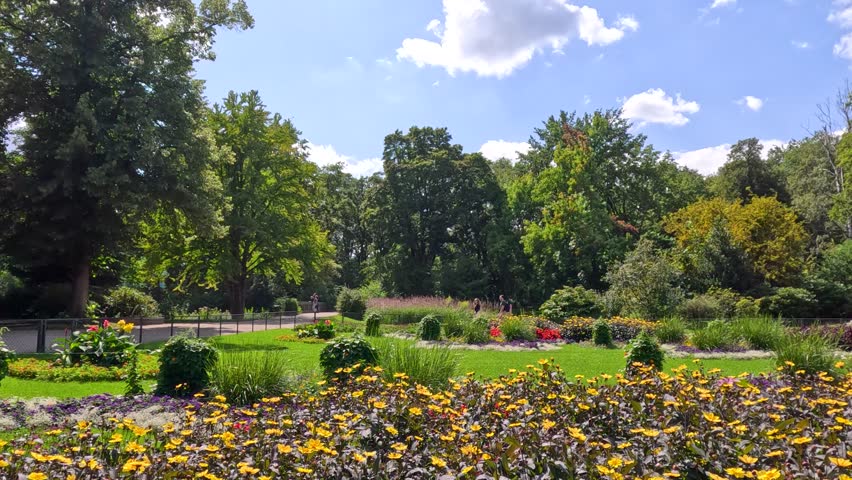 Wide shot of vibrant flower garden in Berlin park on sunny day with lush greenery.