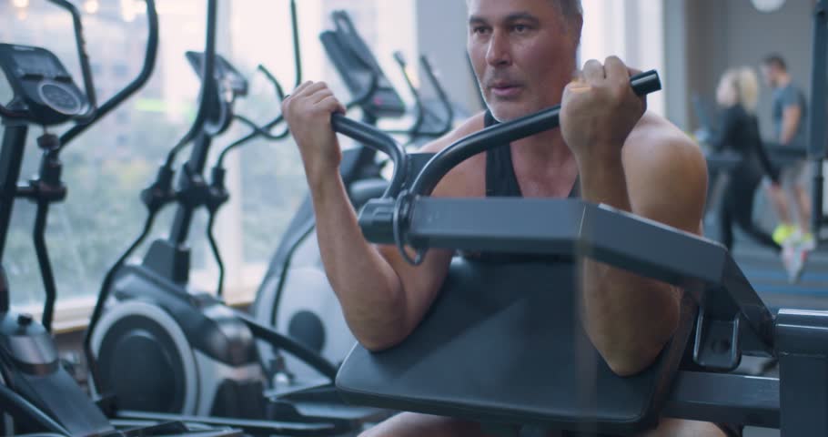 Gym workout. Bicep exercise. Middle aged Caucasian man trains his bicep muscles in the gym. Middle-aged Caucasian man trains biceps with precise form during an intense gym workout.