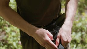 Young man outdoors adjusts tactical gloves and secures straps in forest environment, close up of hands showing careful precise grip, intent focus, skill ful readiness and strength for mission prep - Powered by Shutterstock - Get 15% off with code: PIKWIZARD15