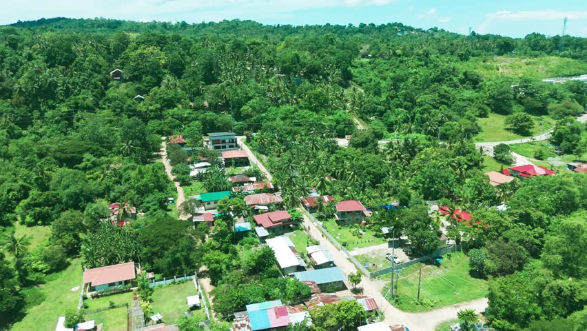 Authentic aerial shot of a rural Philippine village with colorful rooftops and dense green jungle—ideal for culture, documentary, and eco-development visuals.