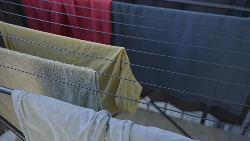 Clean towels and garments neatly placed on drying rack outside. Concept of eco-friendly lifestyle and home routine