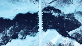 Aerial drone view of fast river with suspension foot bridge. Snow winter forest in Finland  - Powered by Shutterstock - Get 15% off with code: PIKWIZARD15
