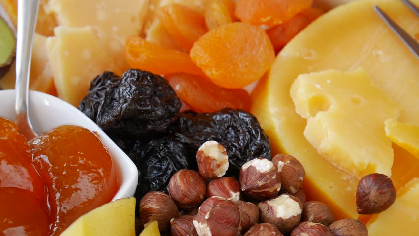 Delicious cheese platter with various accompaniments like dried fruits, nuts, and honey.