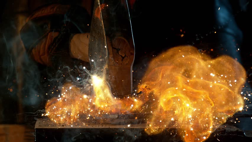 Close-up of blacksmith forging glowing hot iron on anvil with flying sparks. Super slow motion filmed on high-speed cinema camera at 1000 fps