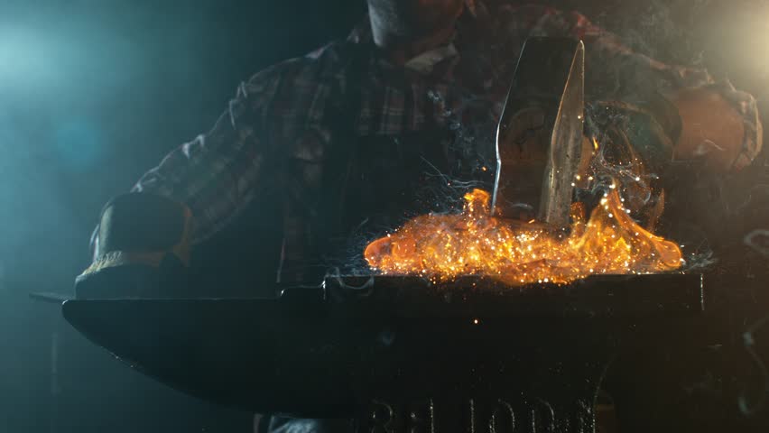Close-up of blacksmith forging glowing hot iron on anvil with flying sparks. Super slow motion filmed on high-speed cinema camera at 1000 fps