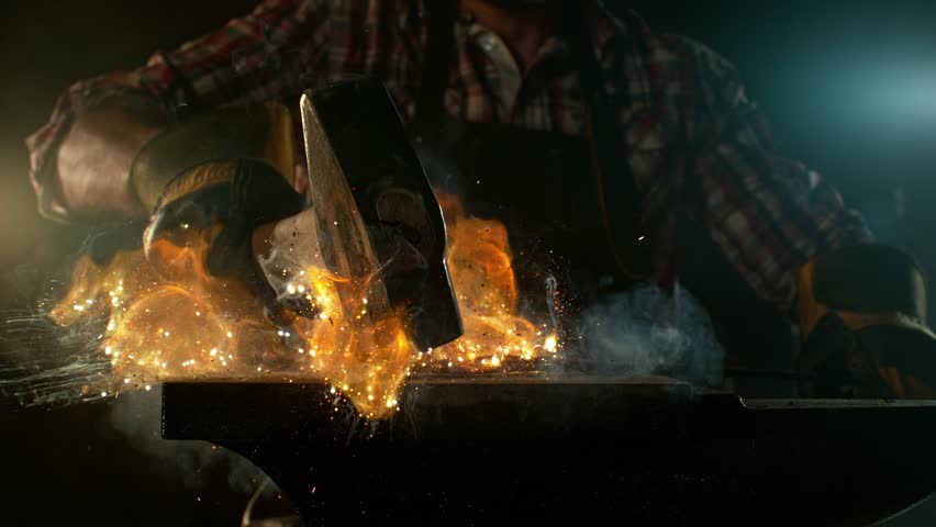 Close-up of blacksmith forging glowing hot iron on anvil with flying sparks. Super slow motion filmed on high-speed cinema camera at 1000 fps