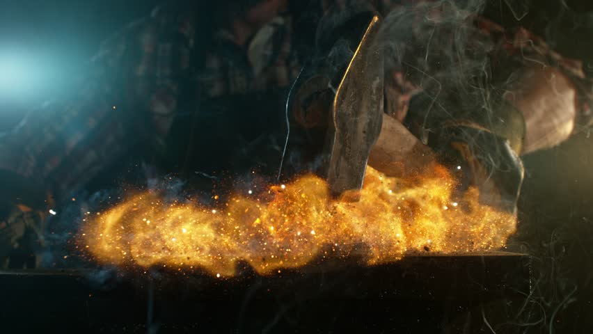 Close-up of blacksmith forging glowing hot iron on anvil with flying sparks. Super slow motion filmed on high-speed cinema camera at 1000 fps