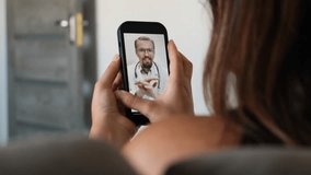 Young woman seen from behind consulting with female doctor via video call using mobile phone. Online healthcare and telemedicine service. Modern medical consultation and remote treatment. - Powered by Shutterstock - Get 15% off with code: PIKWIZARD15