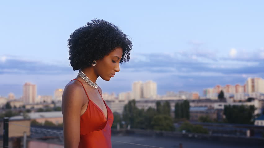 Young African American woman looking at cityscape, feeling lonely after breakup
