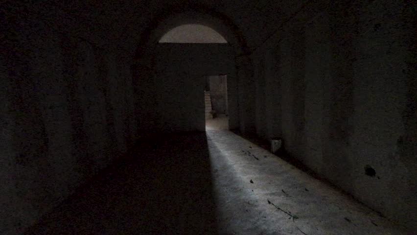 A dimly lit corridor leading to a staircase, with shadows and textured walls. Former ISIS secret military base. Syria, Palmyra.