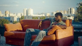 Stylish African American man sitting on red couch on rooftop, modeling shoot - Powered by Shutterstock - Get 15% off with code: PIKWIZARD15