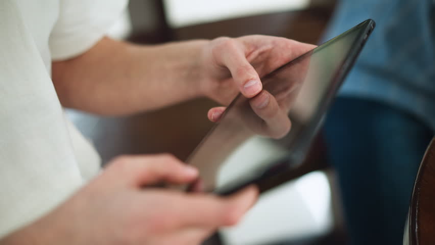 White man wearing white polo tapping tablet screen highlighting sunlike symbol on thumbnail nails in modern workspace close up capturing fingertip gesture on touchscreen interface interaction - Powered by Shutterstock - Get 15% off with code: PIKWIZARD15