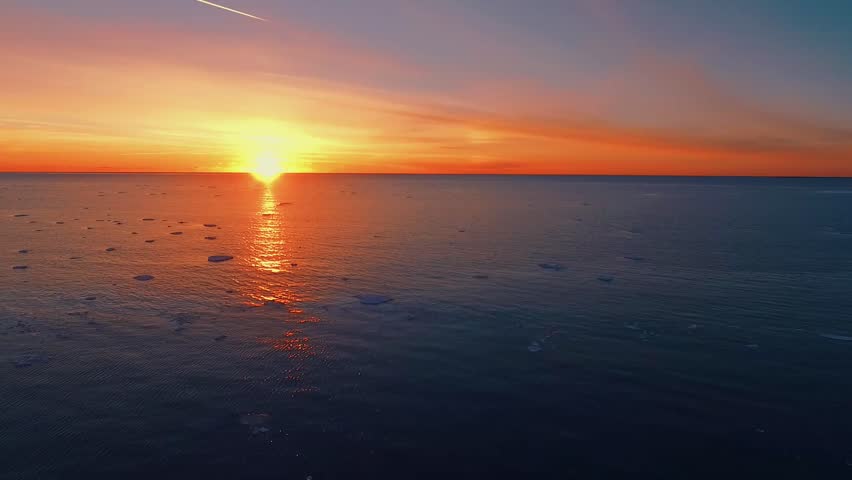 Aerial drone view of sunset sky over iced sea. Beautiful winter landscape in Finland.