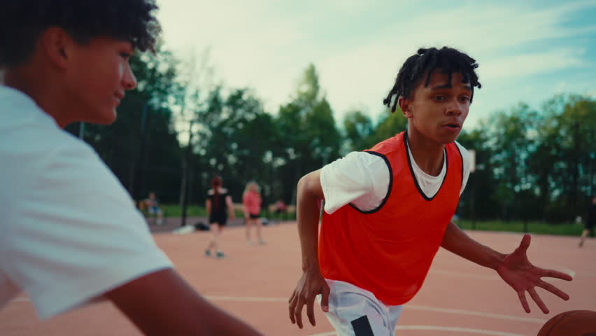 African american teens playing streetball in outdoor court, sport for juniors. Active pastime in weekend, young people spending pastime on basketball court, healthy lifestyle for be strong and active