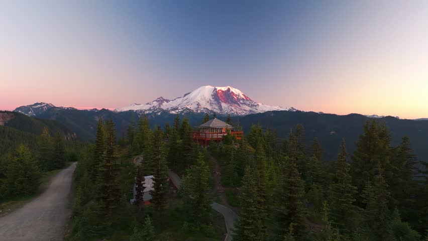 Fire lookout, Sun Top sitting in front of Mount Rainier during a pink sunset.
