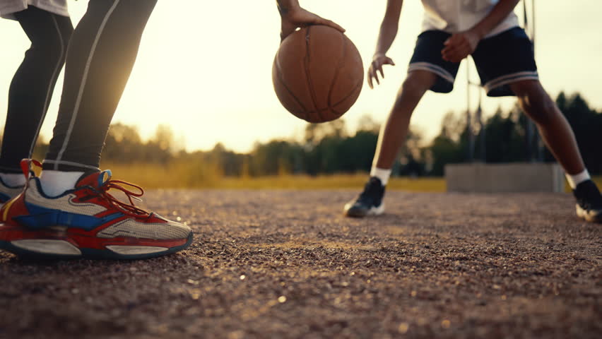 Streetball and basketball, two players training together, bouncing ball, details . Active sport exercise for developing endurance and power of body, teenagers in activewear and sportive sneakers