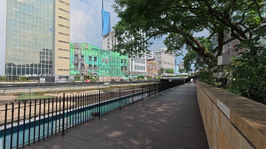 Kuala Lumpur , Kuala Lumpur , Malaysia - 08 27 2025: A beautiful pedestrian walkway along a river in Kuala Lumpur. Designed for easy foot traffic, the path features lush landscaping, shaded areas, and