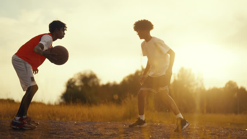 Basketball and streetball, black teens playing outdoors in summer, slow motion. African american adolescents training on open basketball court, sport activity and active leisure, hobby of modern youth