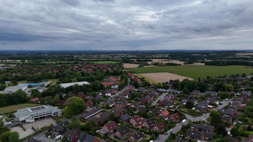 Cloudy day in American town with school building, red brick houses and tennis fields in background. Summer day in Wisconsin, state. Similar to German country. Panorama shot. Farm fields in background.