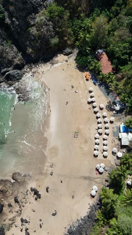 Vertical drone video of Praia do Cachorro in Fernando de Noronha, showing natural pools, turquoise waters, rocky coastline, and an idyllic tropical setting