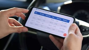 A driver's hands hold a phone displaying a fuel cost tracking application, contemplating expenses. This video is perfect for content on budgeting, car ownership costs, and financial apps. - Powered by Shutterstock - Get 15% off with code: PIKWIZARD15