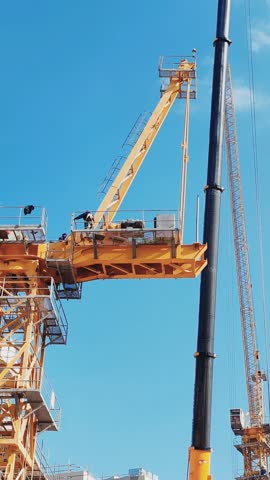 Tower crane or mobile crane erected beside under construction building.
Yellow color Tower crane used for lifting heavy items from ground to top level. Building Cranes for under construction building