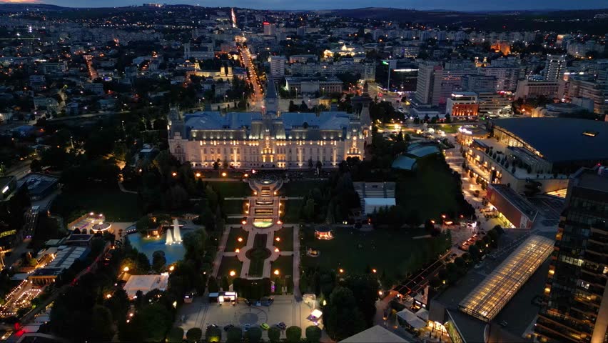 Aerial drone footage of the Iasi cultural palace in the city of Iasi in Romania at night. Beautifully illuminated palace of culture in moldavia. High angle flyover shot of evening urban cityscape.