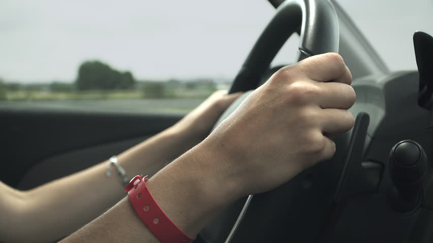 Close-up shot of a woman's hands gripping the steering wheel.