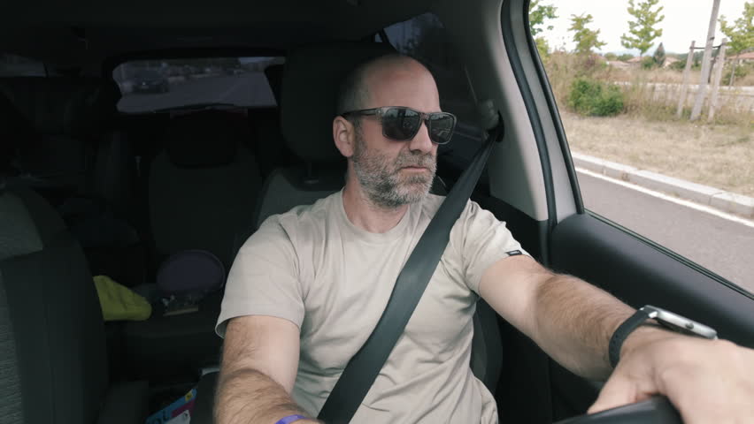 A man driving while wearing sunglasses. View from inside the car.