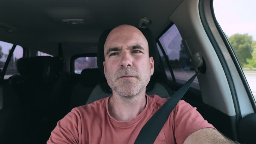 Front view of a man driving with a nervous expression.
