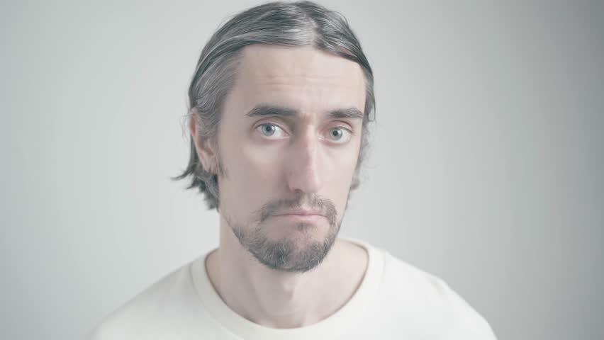 Humorous Young Man's Journey from Seriousness to a Playful Smile in Light-Colored Shirt