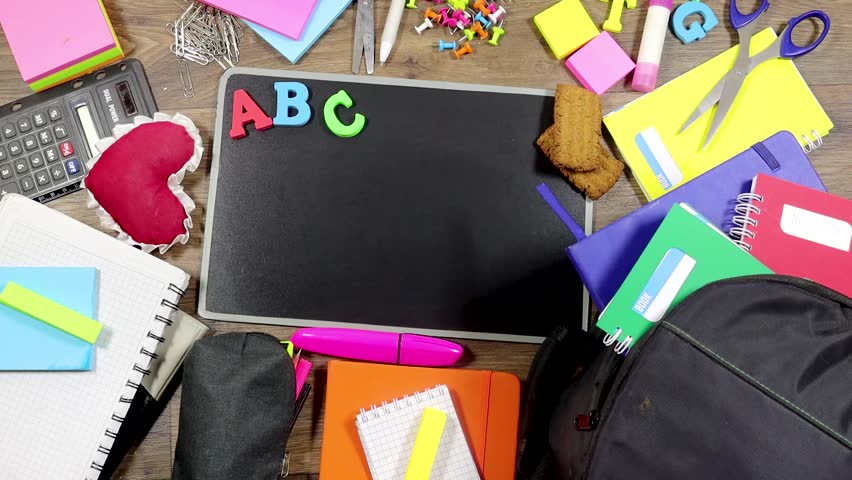 Colorful Back to School Supplies Arranged Around a Chalkboard and woman hand writing