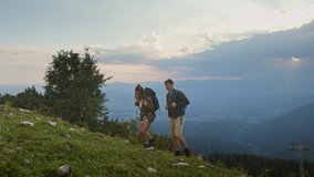 Young couple geared with backpacks, hiking uphill in the mountains at dusk, experience adventure in the great outdoors, wide shot. - Powered by Shutterstock - Get 15% off with code: PIKWIZARD15