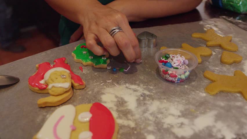 Person decorating Christmas cookies with colorful sprinkles