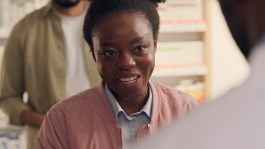 Medicine buying customers in pharmacy African woman smiling health care buying pills drugs pharmacist man help medical assisting cleint buy medication order pharmaceutics at cashier counter drugstore