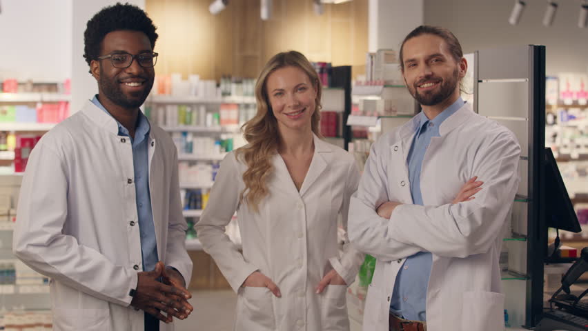Professional team doctors pharmacy consultation physician medic pharmacist in medical coats health care checkup happy multiracial woman men smiling looking camera therapy advice medicine drugstore