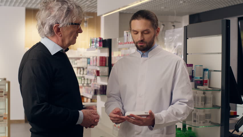 Caucasian pharmacist advice customer medication pills vitamins drugs antibiotics in pharmacy doctor help old senior man patient support medicine consultation health care recommendation in drugstore