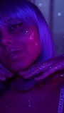 Young cosmic woman with shimmering galactic makeup posing under neon light. Purple wig, glitter, body art, glowing skin. Futuristic beauty look - Powered by Shutterstock - Get 15% off with code: PIKWIZARD15