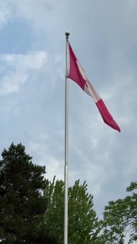 DOLLY SHOT - The Canadian flag prominently flies atop a pole at Centreville Amusement Park on Centre Island, a small island in Lake Ontario, south of mainland Toronto, Ontario, Canada.