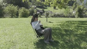 Young woman sitting in a chair on a meadow by the river, enjoying ice cream on a sunny day, relaxing outdoors, embracing nature, leisure, summer treat and peaceful countryside moment - Powered by Shutterstock - Get 15% off with code: PIKWIZARD15